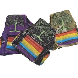 May include: Three canvas backpacks with rainbow stripes and embroidered tree of life designs. The backpacks are purple, black, and green.