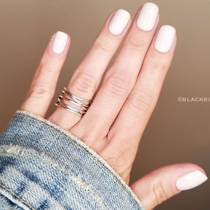 May include: A hand with white nail polish and a silver ring on the ring finger.