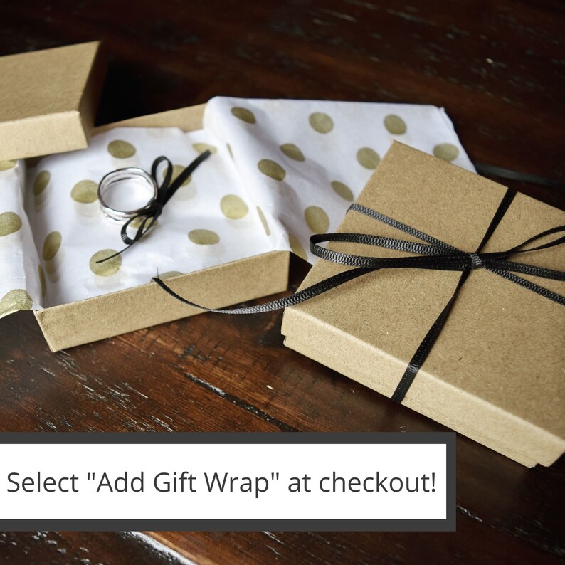 May include: Two brown gift boxes with black ribbon. One box is open and contains a silver ring on white tissue paper with gold polka dots. The text "Select "Add Gift Wrap" at checkout!" is at the bottom of the image.