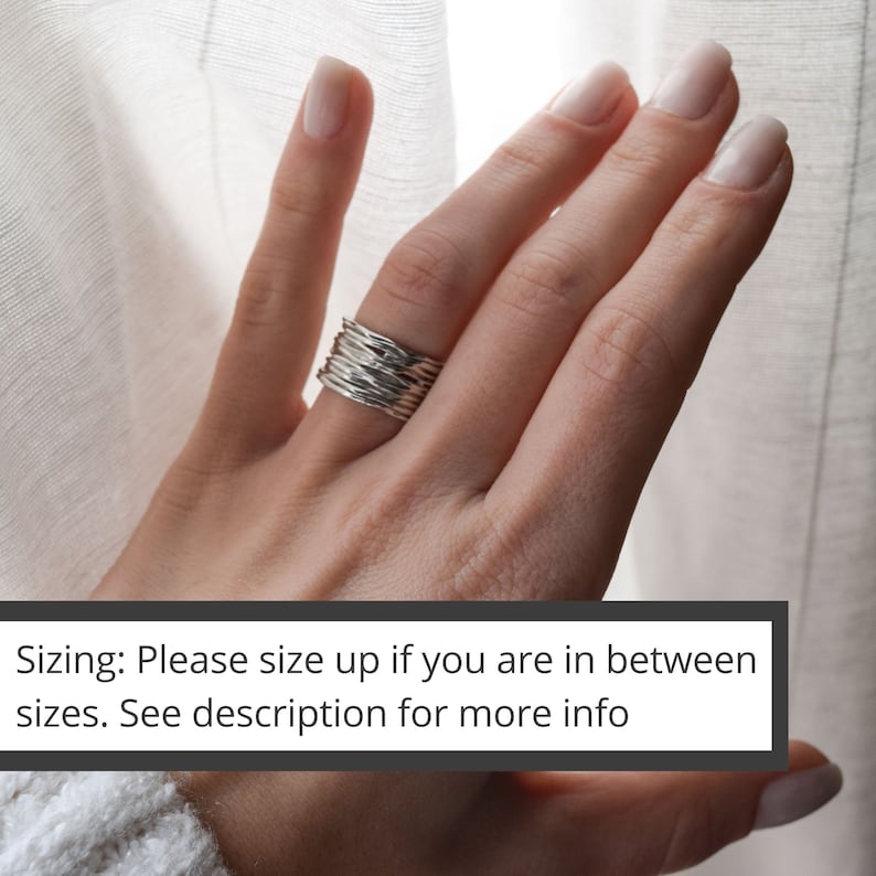 May include: A silver ring with a textured, woven design. The ring is worn on a person's finger. Sizing: Please size up if you are in between sizes. See description for more info