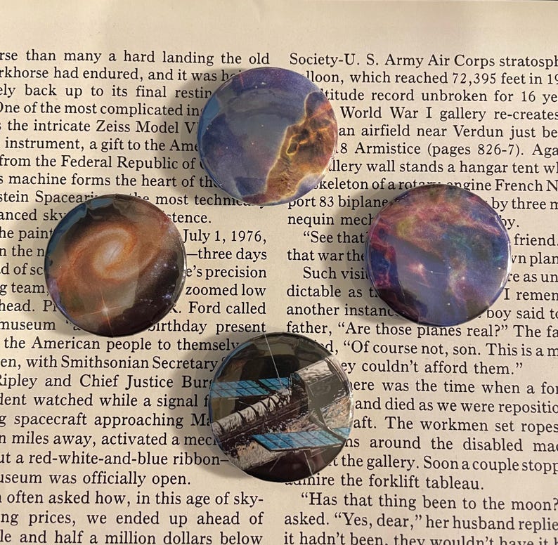 May include: Four colourful pinback buttons with space-themed images. The buttons feature a nebula, a galaxy, a space shuttle, and a quote about planes. The buttons are perfect for adding a touch of space to your belongings.