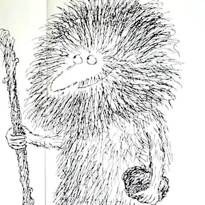 Puede incluir: Una página blanca con una ilustración de dibujos animados de un cavernícola peludo sosteniendo un bastón de madera, con la palabra "CAVEMAN" en letras de bloque naranja. Varias imágenes fijas de películas pequeñas están dispuestas alrededor de la ilustración, que representan escenas de la película.