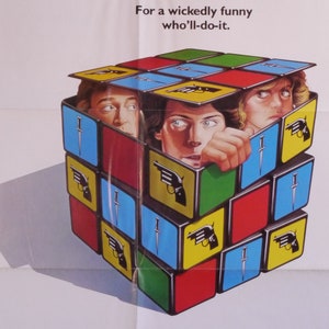 Peut inclure: Affiche de film pour le film "Piège mortel" avec Michael Caine, Christopher Reeve et Dyan Cannon. L'affiche présente un Rubik's Cube avec des images d'armes et les visages des acteurs.