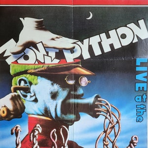 May include: A vintage poster for the Monty Python film "Live at the Hollywood Bowl". The poster features a surreal illustration of a man with a large ear and a microphone, surrounded by worms. The text "Monty Python" is in large, bold letters at the top of the poster.