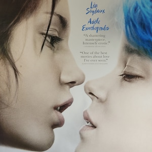 May include: A movie poster for the film "Blue is the Warmest Color" featuring two women, one with blue hair, looking at each other. The poster includes the film's title, the names of the actresses, and the director.