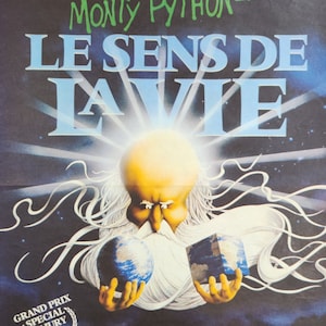 May include: A film poster for "Monty Python: The Meaning of Life" featuring a cartoon depiction of God holding two globes. The poster is in French and includes the text "Grand Prix Special du Jury Cannes 83".