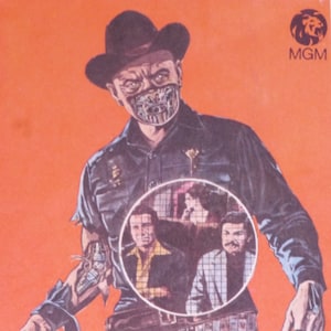 Könnte beinhalten: Ein Mann mit Cowboyhut und einer Metallmaske hält eine Waffe. Er steht vor einem roten Hintergrund mit dem MGM-Logo oben rechts. Der Mann blickt in die Kamera. Im Hintergrund sind weitere Personen zu sehen, die jedoch unscharf sind.