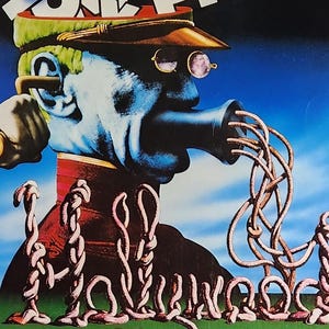 Könnte beinhalten: Ein Vintage-Filmplakat für "Monty Python Live at the Hollywood Bowl". Das Plakat zeigt eine surreale Illustration eines Mannes mit blauem Gesicht und Hut, mit dem Filmtitel in großen, stilisierten Buchstaben. Das Plakat ist überwiegend rot, blau und weiß.