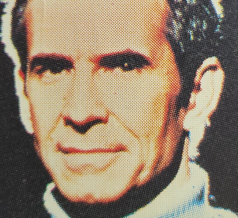 Może przedstawiać: Zbliżenie twarzy mężczyzny. Ma kr&oacute;tkie, ciemne włosy i nosi jasnoniebieską koszulę. Uśmiecha się.