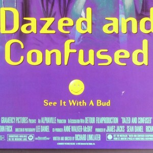 Może przedstawiać: Plakat filmu "Dazed and Confused" z ż&oacute;łtym napisem na fioletowym tle. Plakat zawiera frazę "See It With A Bud" i uśmiechniętą buźkę.