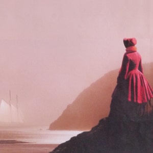 May include: A woman wearing a red coat and hat stands on a rocky cliff overlooking a body of water. A sailboat with white sails is in the distance.