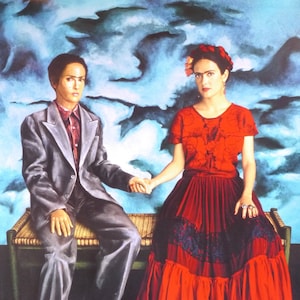 May include: A woman in a red dress with black lace trim and a flower in her hair stands next to a man in a gray suit. They are both looking at the camera and holding hands. The background is a blue and white watercolor painting.