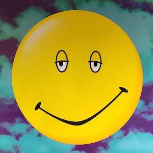 May include: A yellow smiley face with closed eyes and a wide, curved smile against a purple and blue cloudy background.