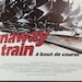 May include: A movie poster for the film "Runaway Train" starring Jon Voight, Eric Roberts, and Rebecca De Mornay. The poster features a close-up of a train engine with the title of the film in red and white letters.