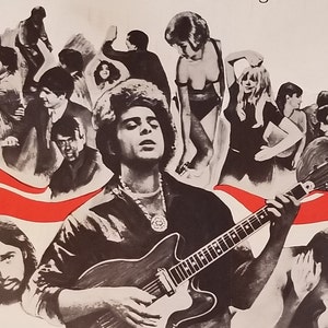 May include: A black and white poster with a man playing a guitar. The man is wearing a black shirt and has long hair. The poster has a red and white stripe across the bottom. The poster is surrounded by other people, some of whom are wearing bathing suits.