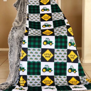 May include: A green and black checkered baby blanket with a repeating pattern of yellow tractors and the words "Little Man".
