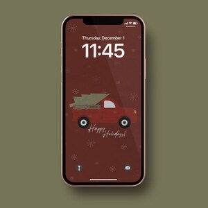 Puede incluir: Una camioneta roja con un árbol de Navidad en la parte trasera, conduciendo sobre un fondo rojo con copos de nieve blancos. El texto "Happy Holidays!" está escrito debajo de la camioneta.