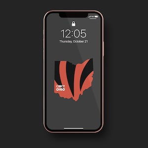 May include: A rose gold smartphone displays a lock screen with the time 12:05 and the date Thursday, October 21. The screen features a stylized map of Ohio in black and orange stripes, with "CINCY OHIO" below.