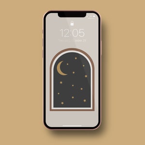 May include: A smartphone with a pink frame and a black screen displaying a digital clock with the time 12:05 and the date Thursday, October 21. The background image is a stylized illustration of a crescent moon and stars in a dark blue sky, framed by a brown arch.