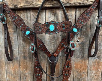 May include: A brown leather horse headstall, breast collar, and reins set with turquoise accents. The set features intricate tooling and stitching.