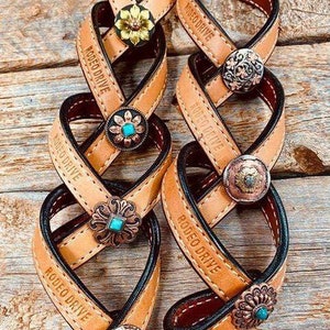 May include: Tan leather braided bracelets with black stitching and decorative metal accents. Each bracelet has the text "Rodeo Drive" engraved on it.