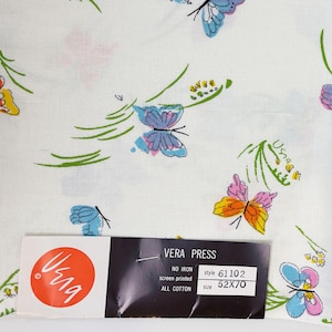 May include: White Vera Press fabric with a colorful butterfly pattern. The butterflies are in shades of blue, pink, and orange, with green stems and yellow accents. The fabric has a tag that reads "VERA PRESS" and "ALL COTTON". The size is 52x70 inches.