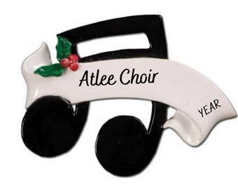 Pode incluir: Adorno de Natal de nota musical preto e branco com uma faixa branca que diz "Atlee Choir" e "YEAR". O adorno tem um ramo de azevinho verde com bagas vermelhas.