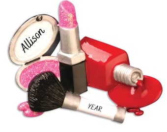 May include: A pink and red makeup ornament with a lipstick, nail polish, and makeup brush. The ornament has the name "Allison" and the word "YEAR" on it.