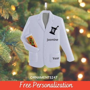 May include: White personalized lab coat Christmas ornament with a pharmacy symbol and a pill bottle. The ornament is decorated with the name "Jasmine" and the year.