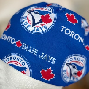 Könnte beinhalten: Blaue Baseballkappe mit dem Logo der Toronto Blue Jays. Die Kappe ist blau mit weißem Text und roten Ahornblatt-Akzenten. Das Teamlogo und das Wort "TORONTO" sind wiederholt auf der Kappe zu sehen.