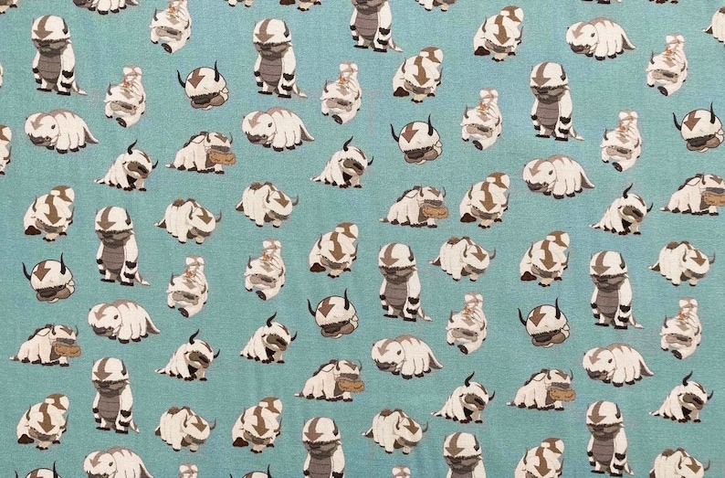 Peut inclure: Un tissu bleu avec un motif r&eacute;p&eacute;t&eacute; de bisons de dessin anim&eacute; blancs et bruns. Les bisons sont dans diverses poses, y compris debout, assis et couch&eacute;s.