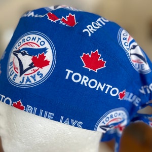 Op de afbeelding: Blauw-witte Toronto Blue Jays baseballpet met een rood esdoornblad en het logo van het team. De pet heeft een strik aan de achterkant.