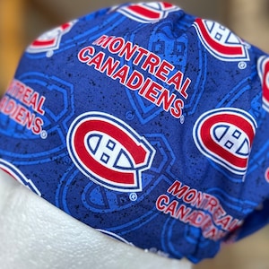 May include: Blue and red fabric scrub hat with a repeating pattern of the Montreal Canadiens logo and the words "Montreal Canadiens".