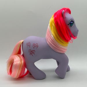 Pode incluir: Um conjunto de três canecas de cerâmica com uma cobertura salpicada de cor creme. Cada caneca apresenta um design pintado à mão diferente: uma folha azul e verde, uma flor amarela e uma baga vermelha. As canecas têm um design simples e moderno.