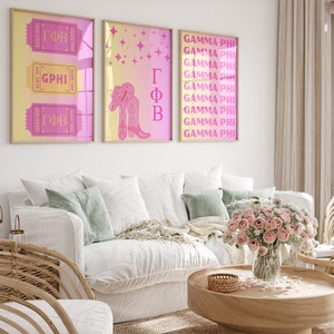 Peut inclure: Trois impressions encadrées avec un fond dégradé rose et jaune. L'impression de gauche présente un billet avec le texte "GΦB est. 1874" répété trois fois. L'impression du centre présente une paire de bottes de cow-boy roses avec un chapeau de cow-boy rose. L'impression de droite présente le texte "GAMMA PHI" répété 10 fois.