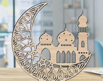 Op de afbeelding: Een houten uitsnijding van een halve maan met ingewikkelde ontwerpen en een moskee in het midden. De moskee heeft drie koepels en een hoge minaret. De uitsnijding is een decoratief stuk voor het huis.