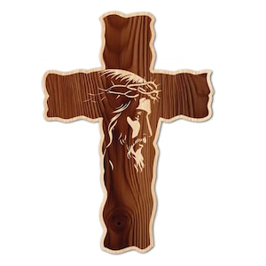 May include: Wooden cross with a light-colored border. The cross features a detailed engraving of Jesus wearing a crown of thorns. The wood grain is visible, adding texture to the religious symbol. The cross is a symbol of faith and Christianity.