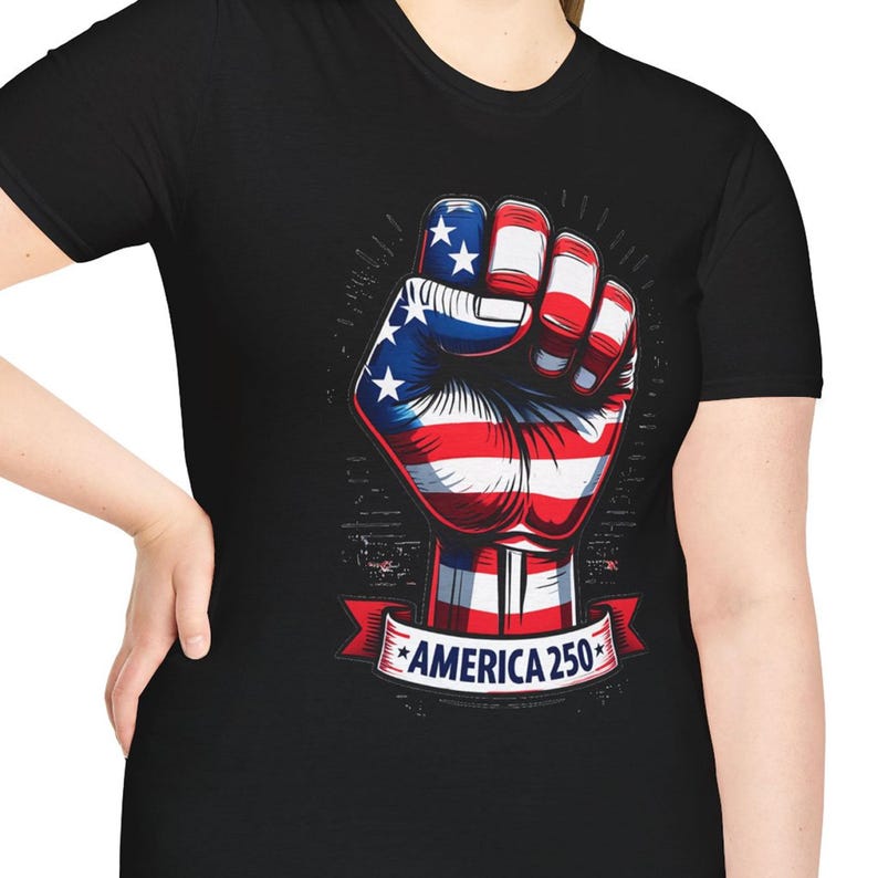 May include: Black t-shirt featuring a graphic of a clenched fist in the colors of the American flag: red, white, and blue. The design includes stars and stripes, with the text "AMERICA 250" on a banner below the fist.