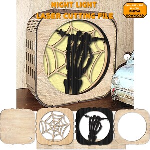 Op de afbeelding: Een lasergesneden houten nachtlampje met een skelethand die uit een spinnenweb reikt. Het nachtlampje is gemaakt van hout en heeft een lichtgele gloed. Het ontwerp is perfect voor Halloween-decoratie.