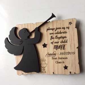 May include: A wooden sign with a black silhouette of an angel playing a trumpet. The sign has the text "please join us as we celebrate The Baptism of our child MURAT Sunday - 28/07/2019 Sent Antuan Church".