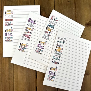 May include: Four white notepads with lined pages and colorful text. The notepads are labeled "Mrs. Ried," "Mrs. Taylor," "Mrs. Barker," and "Mrs. Fennell." The text is in a playful font with crayon and pencil designs.