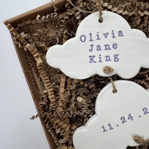 personalised Clay cloud wall hanging keepsake decoration ornament. three clouds attached to each other with twine for nursery wall art. First cloud has baby’s name, middle cloud baby weight and third cloud birth date. handpainted in choice of colour