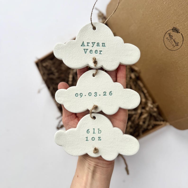personalised Clay cloud wall hanging keepsake decoration ornament. three clouds attached to each other with twine for nursery wall art. First cloud has baby’s name, middle cloud baby weight and third cloud birth date. handpainted in choice of colour
