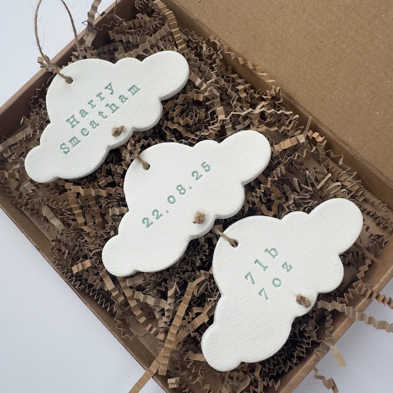 personalised Clay cloud wall hanging keepsake decoration ornament. three clouds attached to each other with twine for nursery wall art. First cloud has baby’s name, middle cloud baby weight and third cloud birth date. handpainted in choice of colour
