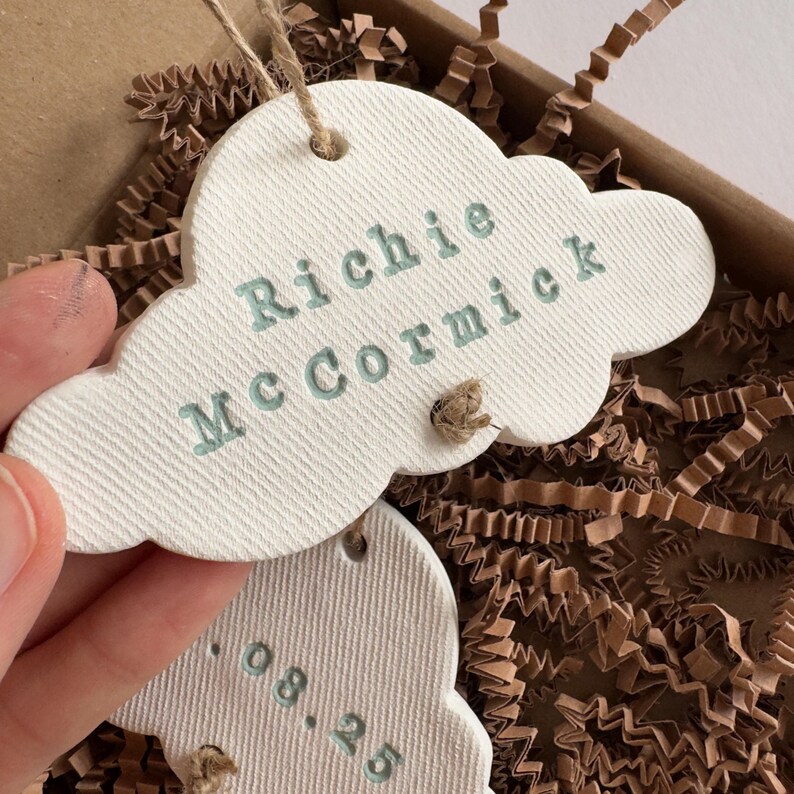 personalised Clay cloud wall hanging keepsake decoration ornament. three clouds attached to each other with twine for nursery wall art. First cloud has baby’s name, middle cloud baby weight and third cloud birth date. handpainted in choice of colour