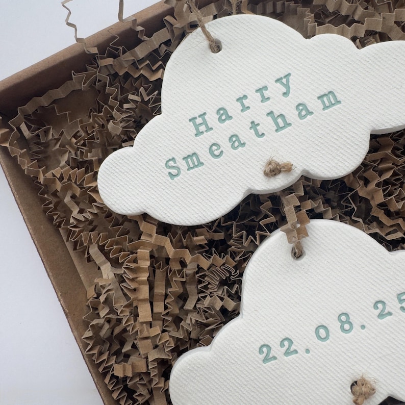 personalised Clay cloud wall hanging keepsake decoration ornament. three clouds attached to each other with twine for nursery wall art. First cloud has baby’s name, middle cloud baby weight and third cloud birth date. handpainted in choice of colour