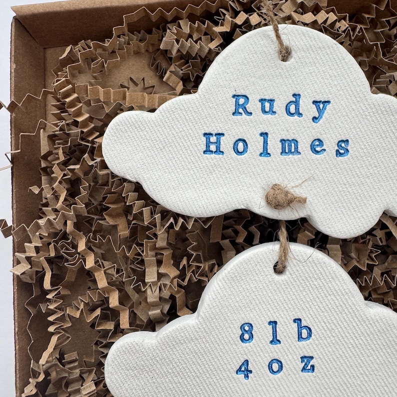 personalised Clay cloud wall hanging keepsake decoration ornament. three clouds attached to each other with twine for nursery wall art. First cloud has baby’s name, middle cloud baby weight and third cloud birth date. handpainted in choice of colour