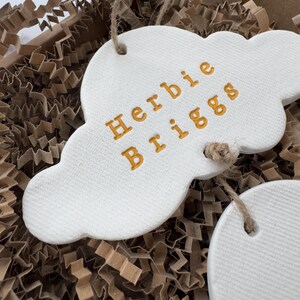 personalised Clay cloud wall hanging keepsake decoration ornament. three clouds attached to each other with twine for nursery wall art. First cloud has baby’s name, middle cloud baby weight and third cloud birth date. handpainted in choice of colour
