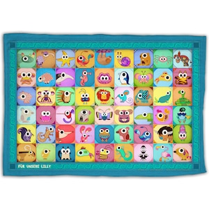 Op de afbeelding: Een kleurrijk quilt met een blauwe rand en een verscheidenheid aan dierenfiguren met grote ogen. De quilt heeft de tekst "FUR UNSERE LILLY" onderaan.