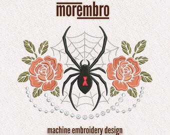 May include: Machine embroidery design featuring a black widow spider with a red hourglass marking, set against a spiderweb. Flanking the spider are two peach-colored roses with green leaves, and a string of pearls. The text "morembro" and "machine embroidery design" are also present.